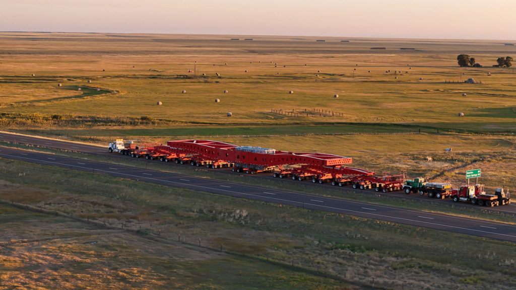 An Omega Morgan heavy haul truck pulling a 500-ton IRH suspension trailer on a remote road.