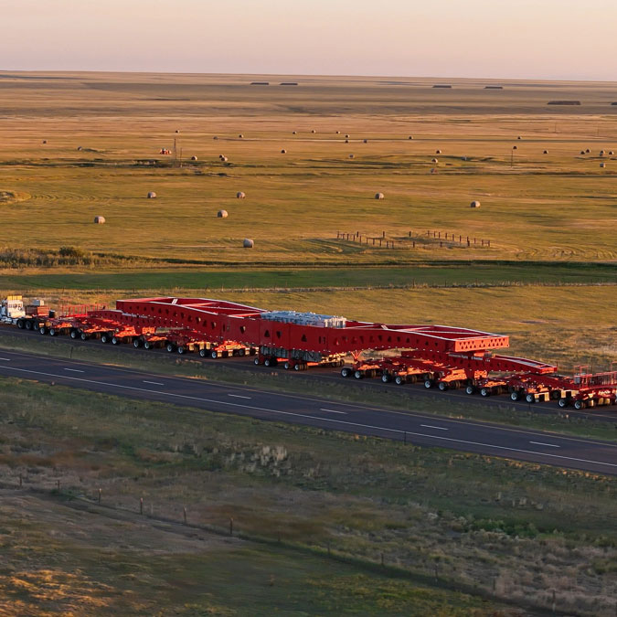 An Omega Morgan heavy haul truck pulling a 500-ton IRH suspension trailer on a remote road.