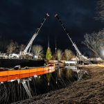 2 Omega Morgan cranes, head-to-head, over water.