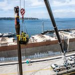 A beautiful view of the Seattle waterfront while the crane crew secures straps down the totem pole in five-foot segments.