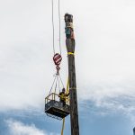 A member of the Omega Morgan crane crew in a man basket securing rigging to the top of the pole.