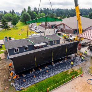 The Omega Morgan Crane crew uses their 350-ton crane to guide one-half of a modular classroom into place.