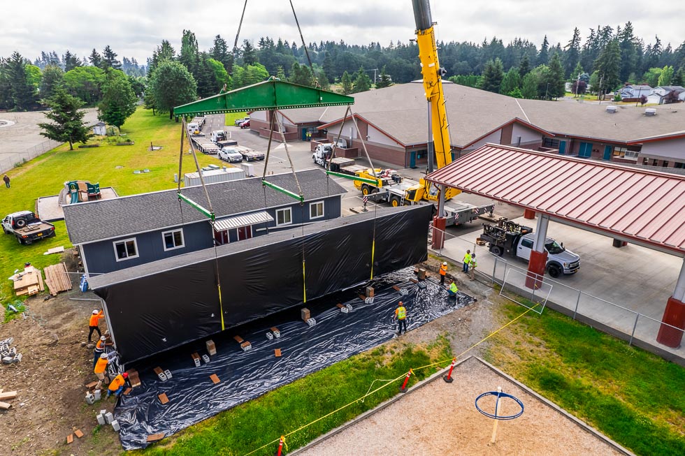 The Omega Morgan 350-ton crane slides a modular classroom into place with the guidance of the crane crew.