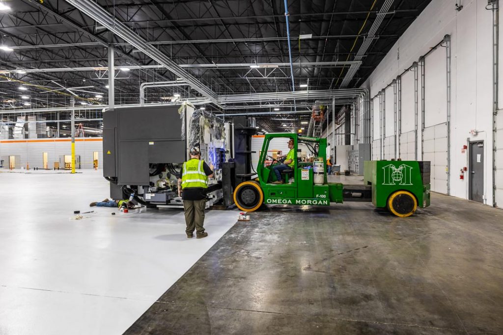 A side view of an Omega Morgan crew relocating a spindle machine with their fork lift.