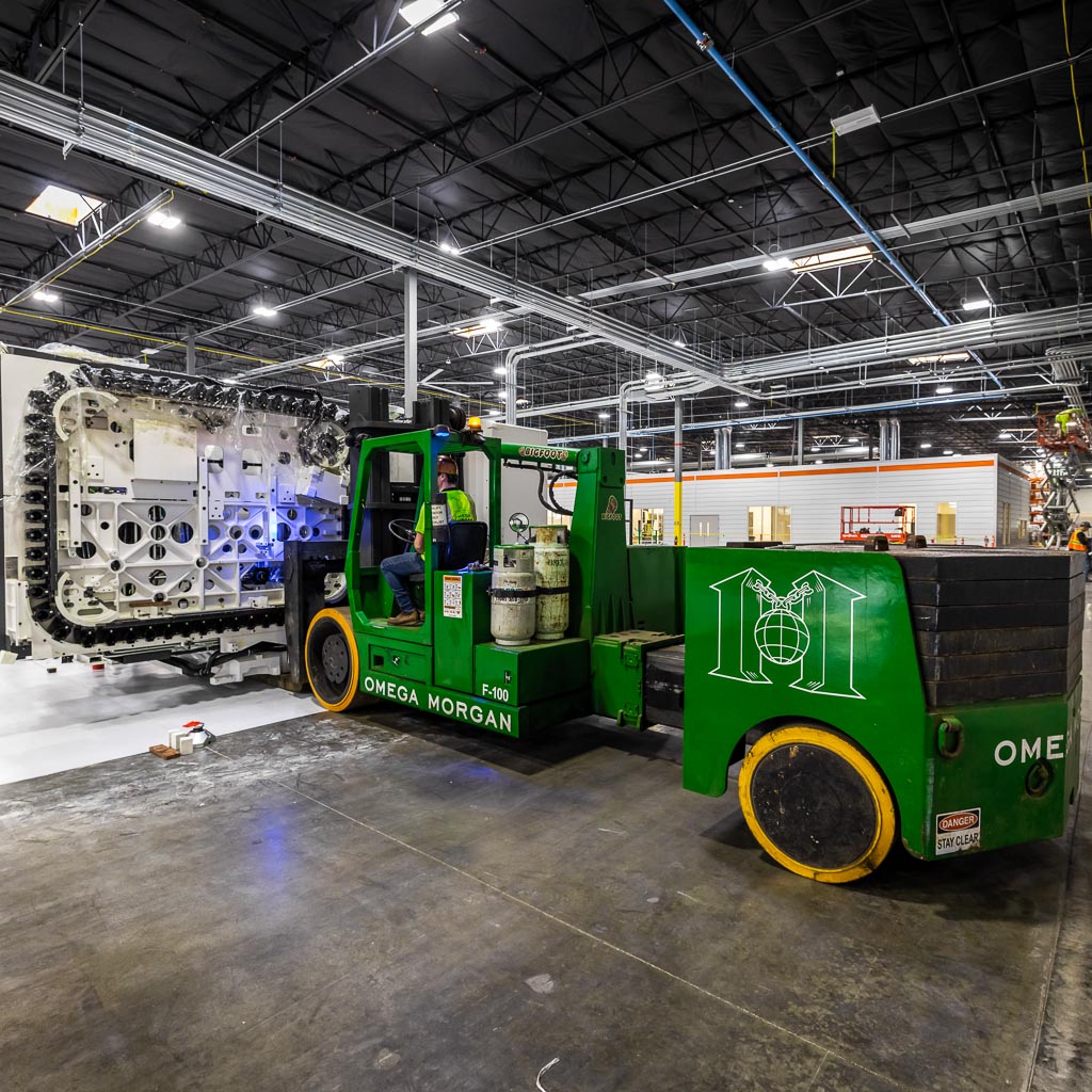 The side view of an Omega Morgan forklift moving a 54,000-pound spindle machine.