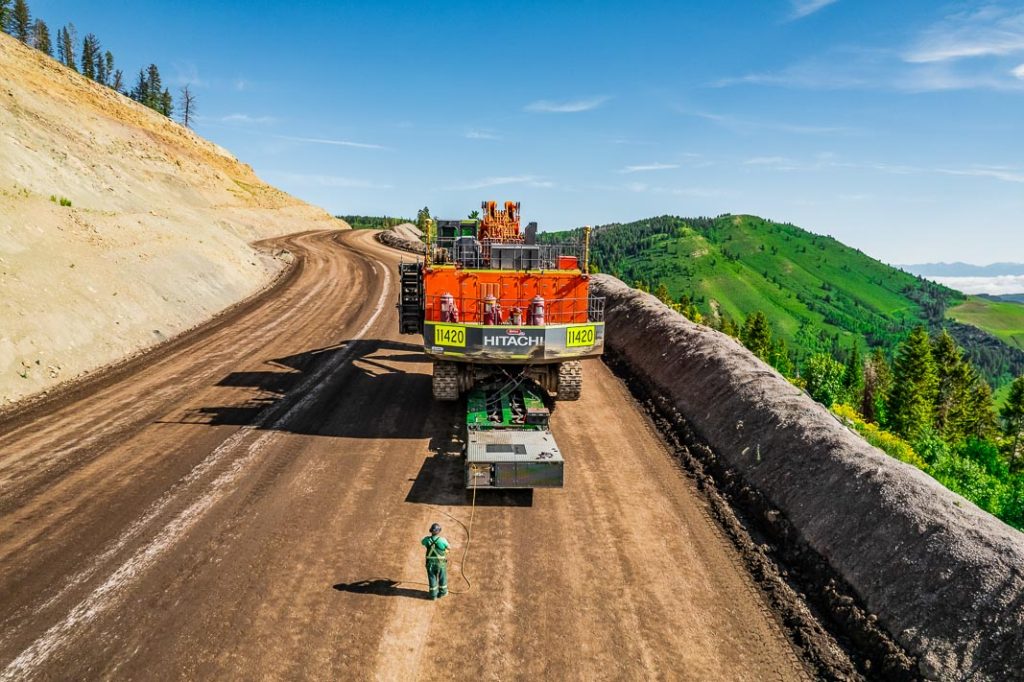 Following closely behind, an Omega Morgan specialized transportation crew member uses special equipment to ensure the mining shovel transports safely up a steep grade.