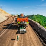 Following closely behind, an Omega Morgan specialized transportation crew member uses special equipment to ensure the mining shovel transports safely up a steep grade.
