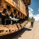 A crew member expertly guides the Omega Morgan heavy haul truck as it transports a mining shovel up a steep mountain road.
