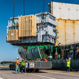 A 299,829-pound transformer being lowered from a shipping vessel onto our trailer and being received by the Omega Morgan specialized transportation crew.