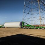Double Schnabel trailer attaching to a massive wind energy component before its saddles are removed and it’s ready for transport.